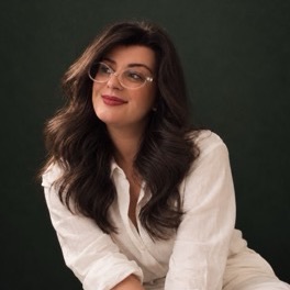 Nattália Silveira, de camisa branca e óculos, sorrindo